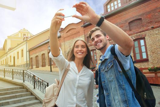 Happy couple of tourists taking selfie in old city.