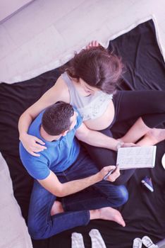 top view of a happy pregnant couple checking a list of things for their unborn baby at home on the floor