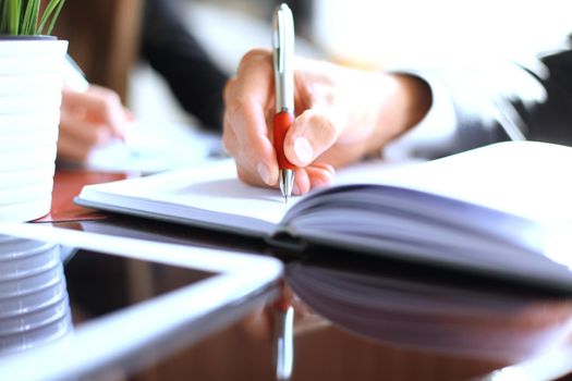 Unrecognizable business person analyzing graphs and taking notes