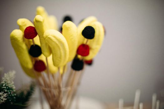 a dessert of banana and berry marshmallows on sticks in a beautiful glass jar