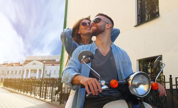 happy young couple riding scooter in town. Handsome guy and young woman travel. Adventure and vacations concept.