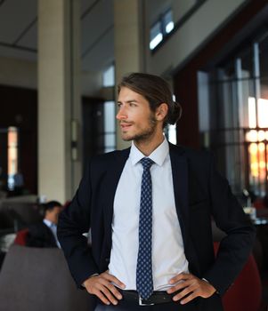 Portrait of happy young businessman standing in hotel lobby.