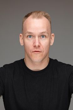 Close-up photo of surprised Caucasian man in black shirt posing for camera