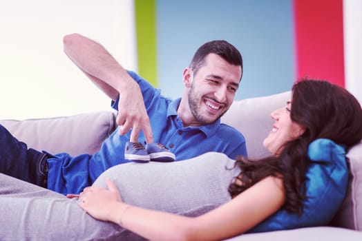 happy pregnant couple relaxing on sofa couch at home