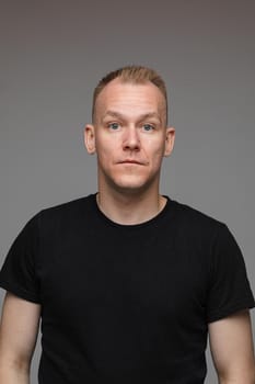 adult caucasian man in black t-shirt and short hair looks to the camera and smiles