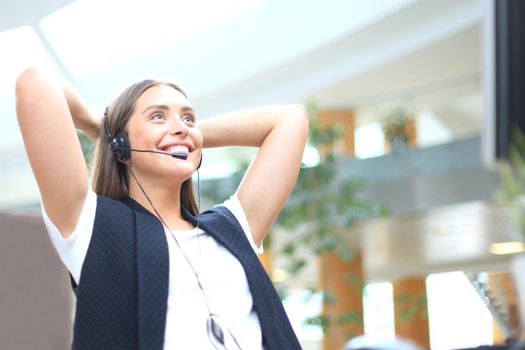 Call center operator in headset resting at workplace in office.