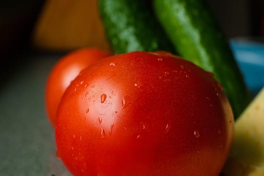 Picture with focus on washed red tomato lies on the table with drops of water on it