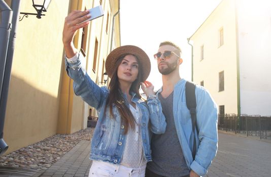 Happy couple of tourists taking selfie in old city.