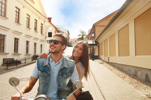 happy young couple riding scooter in town. Handsome guy and young woman travel. Adventure and vacations concept.