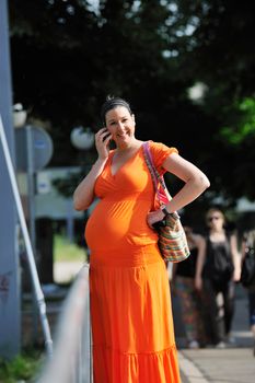 BEAUTIFUL YOUNG PREGNANT WOMAN WALKING OUTDOOR AND TAKING ON CELLPHONE