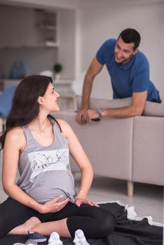 a happy pregnant couple checking a list of things for their unborn baby at home on the floor