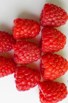 Stock photo close-up of juicy raspberries sorted on white background. Isolated on white background.