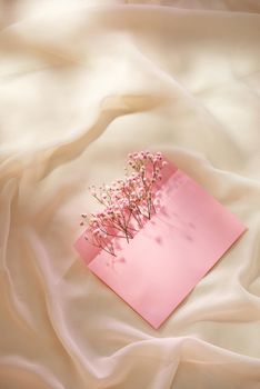 Pink envelope with a spring flower arrangement. Flat lay, top view