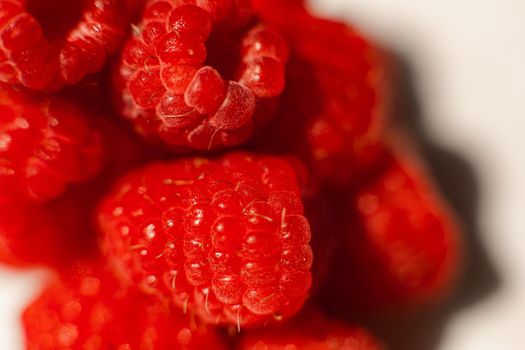 Stock photo close-up of pile of sweet and ripe raspberries in daylight. Raspberries texture.