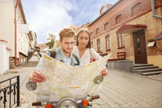 Young Couple with scooter looking at map.