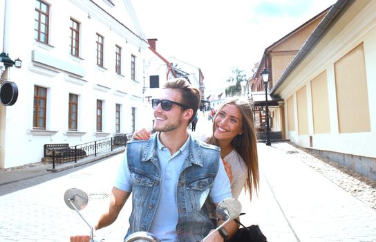 happy young couple riding scooter in town. Handsome guy and young woman travel. Adventure and vacations concept.