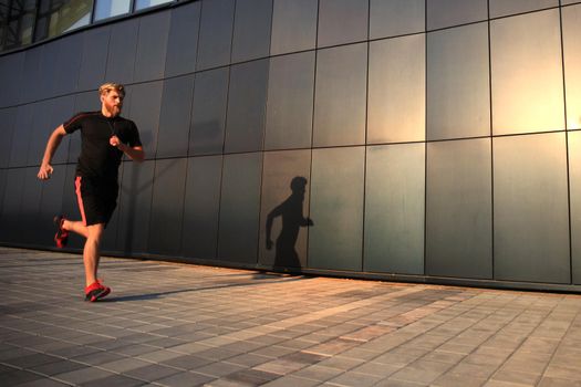 Sporty young man running outdoors to stay healthy, at sunset or sunrise. Runner