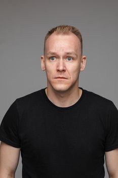 adult caucasian man in black t-shirt and short hair looks aside and thinks