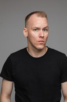 adult caucasian man in black t-shirt and short hair looks aside and thinks