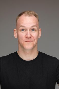 Close-up photo of amicable man in black shirt posing for his passport picture