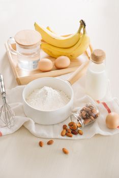 ingredients and tools to make banana cake on white background