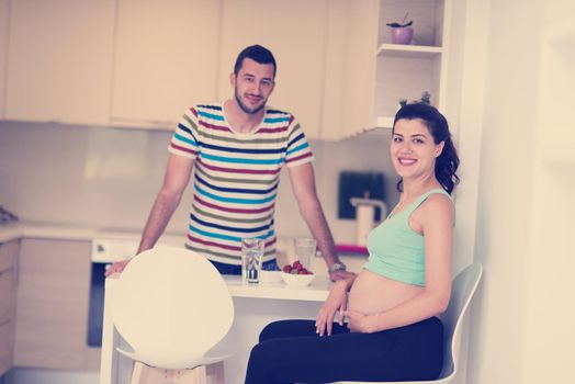 young pregnant couple eating strawberries at kitchen, lifestyle healthy pregnancy happy life concept