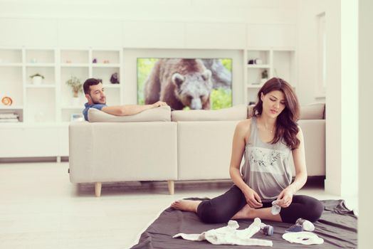 a happy pregnant couple checking a list of things for their unborn baby at home on the floor