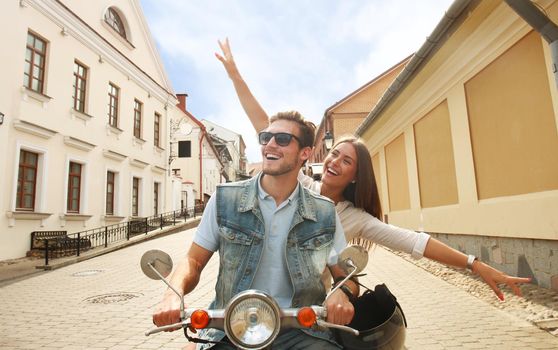 happy young couple riding scooter in town. Handsome guy and young woman travel. Adventure and vacations concept.