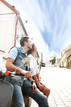 happy young couple riding scooter in town. Handsome guy and young woman travel. Adventure and vacations concept.