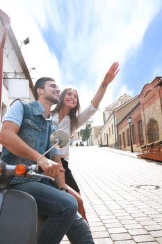 happy young couple riding scooter in town. Handsome guy and young woman travel. Adventure and vacations concept.