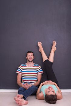 happy pregnant couple relaxing in front of black chalkboard on the floor at home