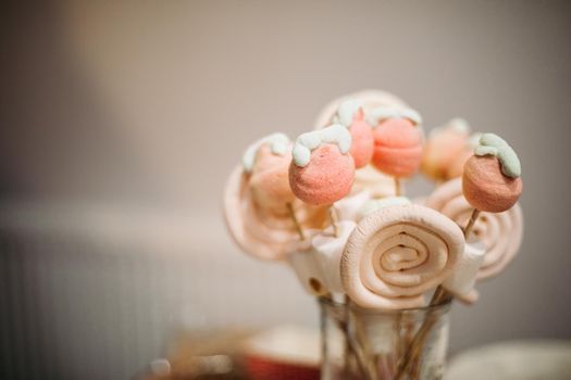 Close-up of delicious sweet and soft candies made from sugar and yolk on wooden sticks in glass. Copy space.