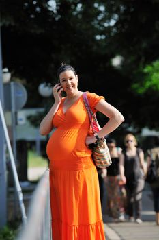 BEAUTIFUL YOUNG PREGNANT WOMAN WALKING OUTDOOR AND TAKING ON CELLPHONE