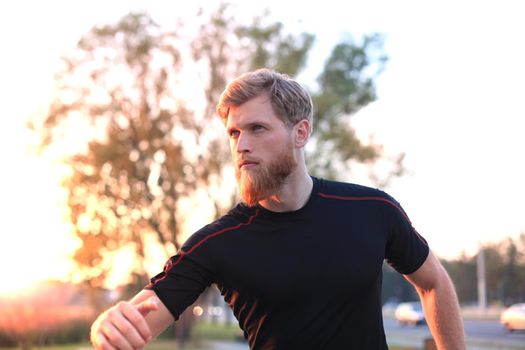 Fit athlete. Handsome adult man running outdoors to stay healthy, at sunset or sunrise. Runner