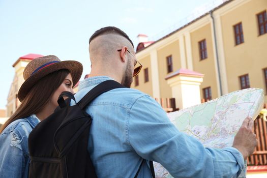 Happy couple walking outdoors sightseeing and holding a map.