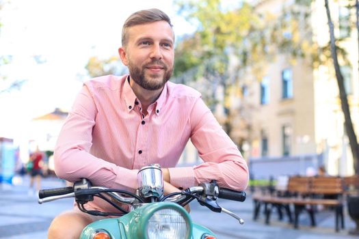 Handsome man posing on a scooter in a vacation context. Street fashion and style