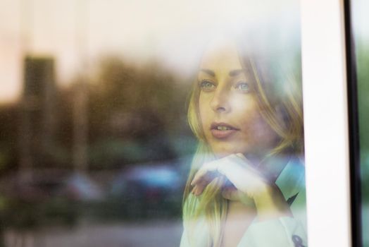 photo from behind the glass: a successful business woman looks out the window of his office. the photo has a empty space for your text