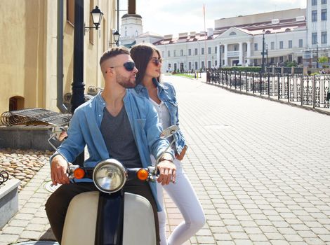 happy young couple riding scooter in town. Handsome guy and young woman travel. Adventure and vacations concept.