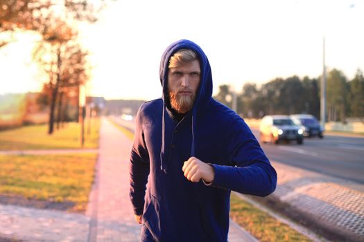 Handsome young man doing stretching exercises before running while standing outdoors