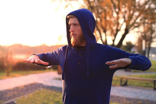 Handsome young man doing stretching exercises before running while standing outdoors