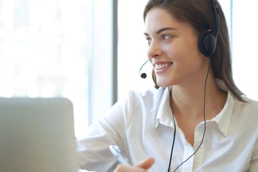 Female customer support operator with headset and smiling.