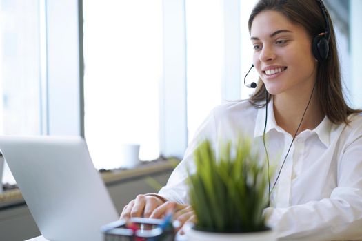 Female customer support operator with headset and smiling.