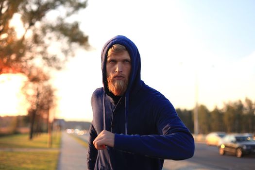 Fit athlete. Handsome adult man running outdoors to stay healthy, at sunset or sunrise. Runner.