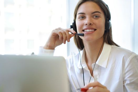 Female customer support operator with headset and smiling.