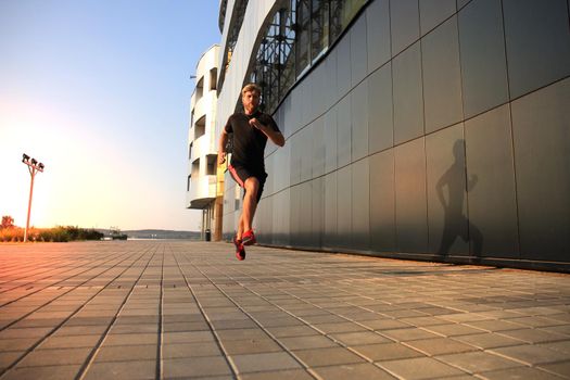 Sporty young man running outdoors to stay healthy, at sunset or sunrise. Runner