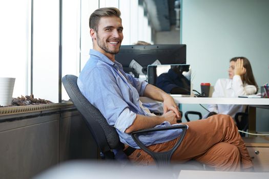 Portrait of a happy young casual businessman at office, smiling.