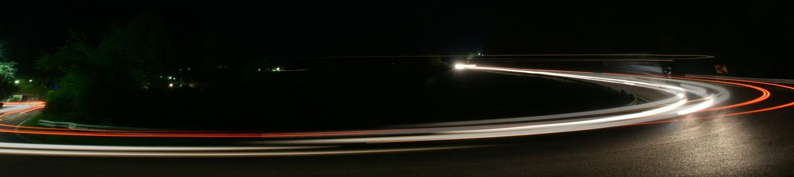 vegicle light trails in night on busy countryroad curve  long exposure