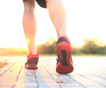 African man legs running while exercising outdoors, at sunrise or sunset.