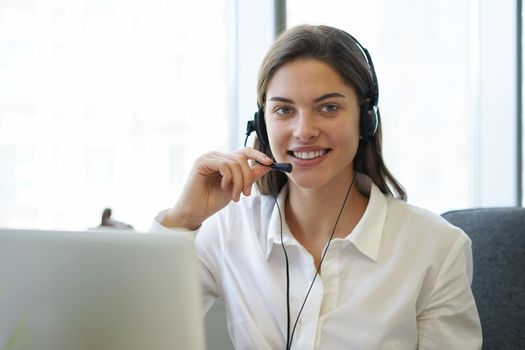 Female customer support operator with headset and smiling.