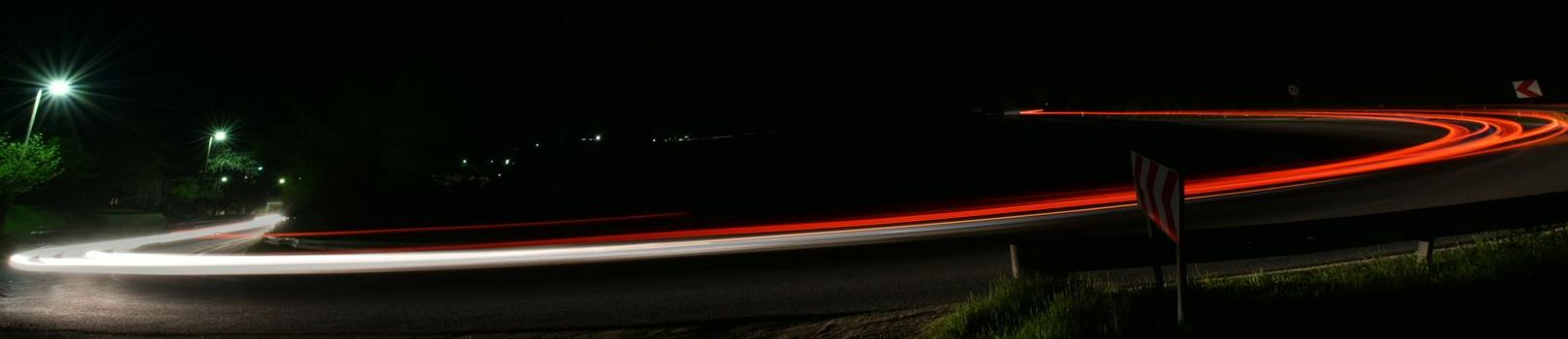 vegicle light trails in night on busy countryroad curve  long exposure